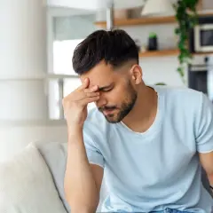 Homme fatigué se tenant la tête, peut-être à cause d'une cigarette électronique et d'un mal de tête.