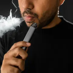 Un homme fume une cigarette électronique, une habitude qui peut avoir des conséquences sur le diabète.