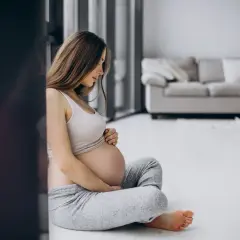 Femme enceinte assise, pensant aux dangers de la cigarette électronique pendant la grossesse.