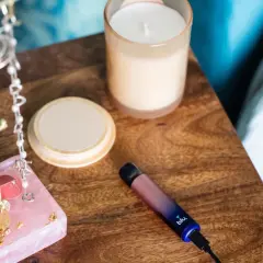 Sur la table de nuit, une cigarette blu clignote bleu. À côté, des bijoux et une bougie.
