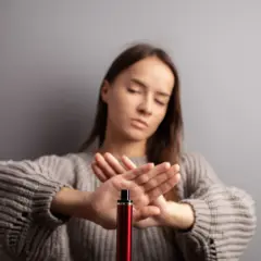 Une jeune femme refuse le montage cigarette électronique, les mains croisées en signe d'arrêt.