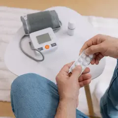 Un homme tient une plaquette de pilules, à côté d'un tensiomètre. Le vapotage peut affecter la tension artérielle.