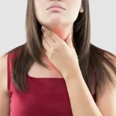 Une femme se tient la gorge, rouge et douloureuse, peut-être à cause d'une cigarette électronique.
