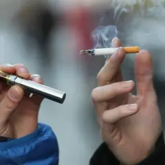 Deux mains tiennent une cigarette électronique et une cigarette allumée, symbolisant les différentes formes de consommation de nicotine et leur origine.