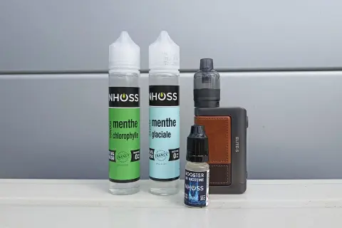Flacons de e-liquide menthe et booster de nicotine, avec une cigarette électronique. Le propylène glycol, composant principal, peut présenter un danger s'il est mal utilisé.