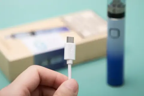 Main tenue, câble USB blanc pour recharger un appareil Innokin low volt.