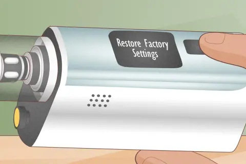 Main d'une personne tenant un appareil électronique avec un écran affichant "Restore Factory Settings". L'atomizer est visible sur le côté gauche.