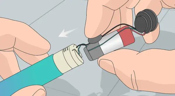 Mains pour recharger les accus d'un appareil électronique. Les fils sont connectés à une batterie et à un composant circulaire.