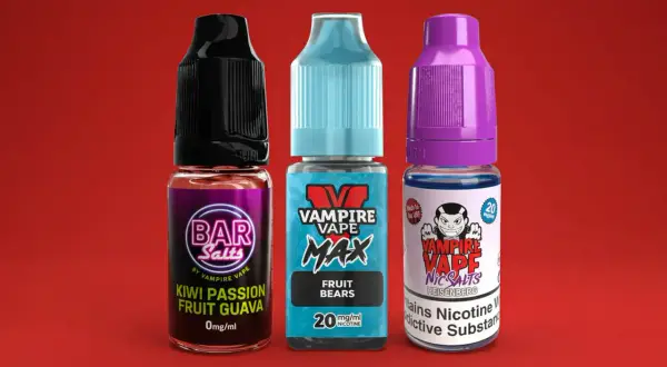 Trois flacons de e-liquide Vampire Vape, dont un Heisenberg, sur fond rouge.