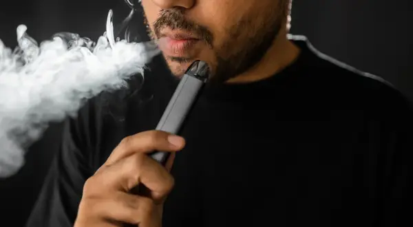 Un homme fume une cigarette électronique, une habitude qui peut avoir des conséquences sur le diabète.