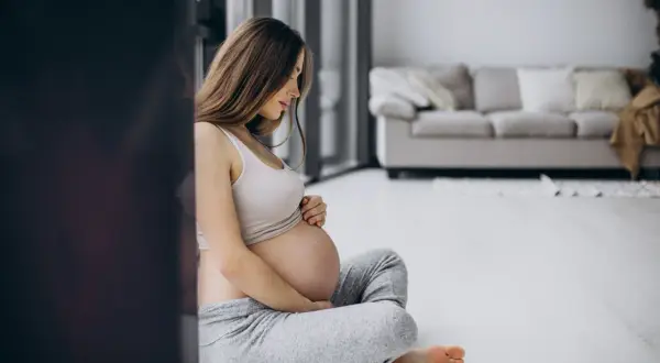 Femme enceinte assise, pensant aux dangers de la cigarette électronique pendant la grossesse.