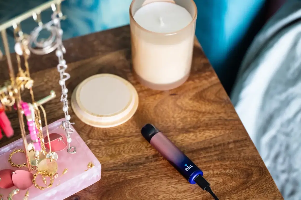 Sur la table de nuit, une cigarette blu clignote bleu. À côté, des bijoux et une bougie.