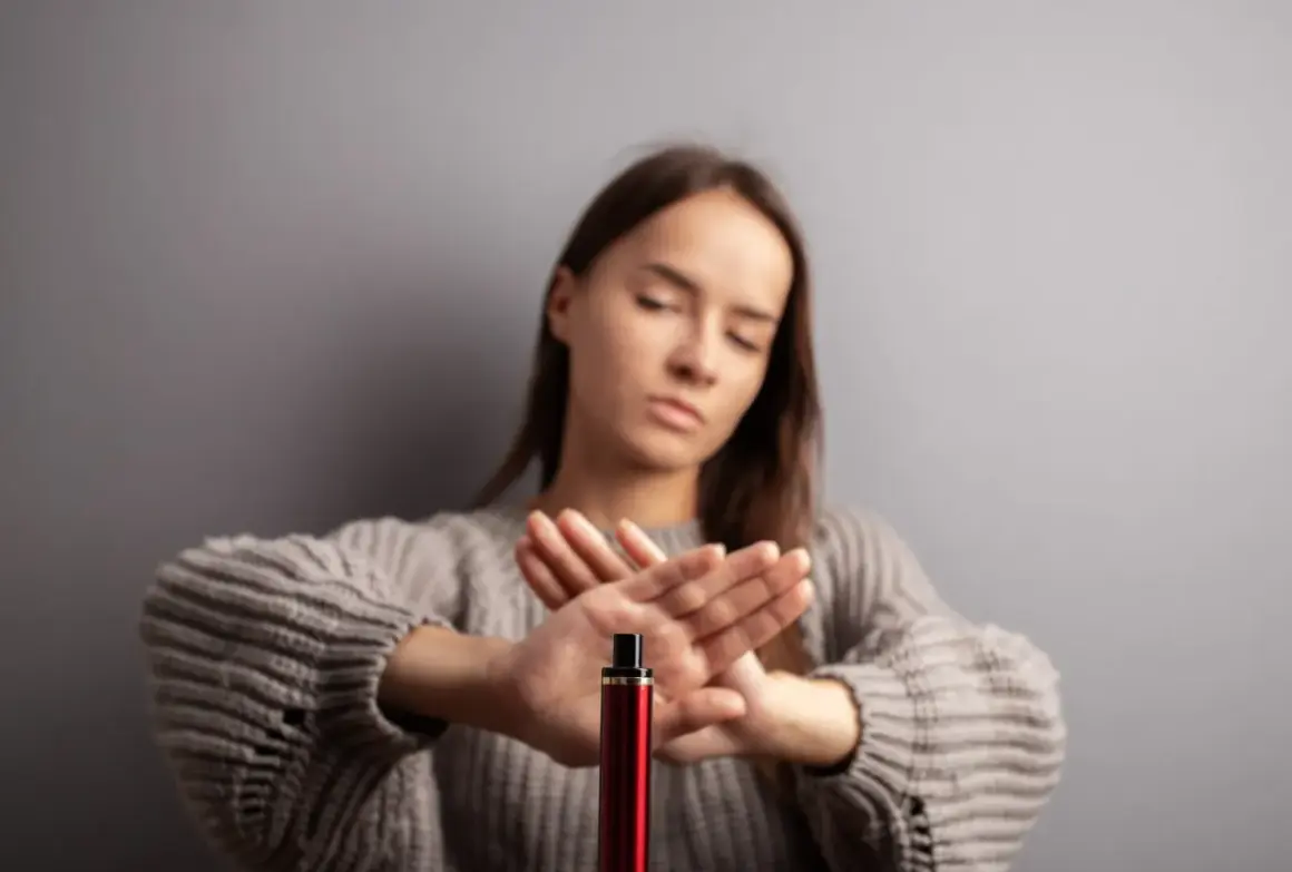Une jeune femme refuse le montage cigarette électronique, les mains croisées en signe d'arrêt.