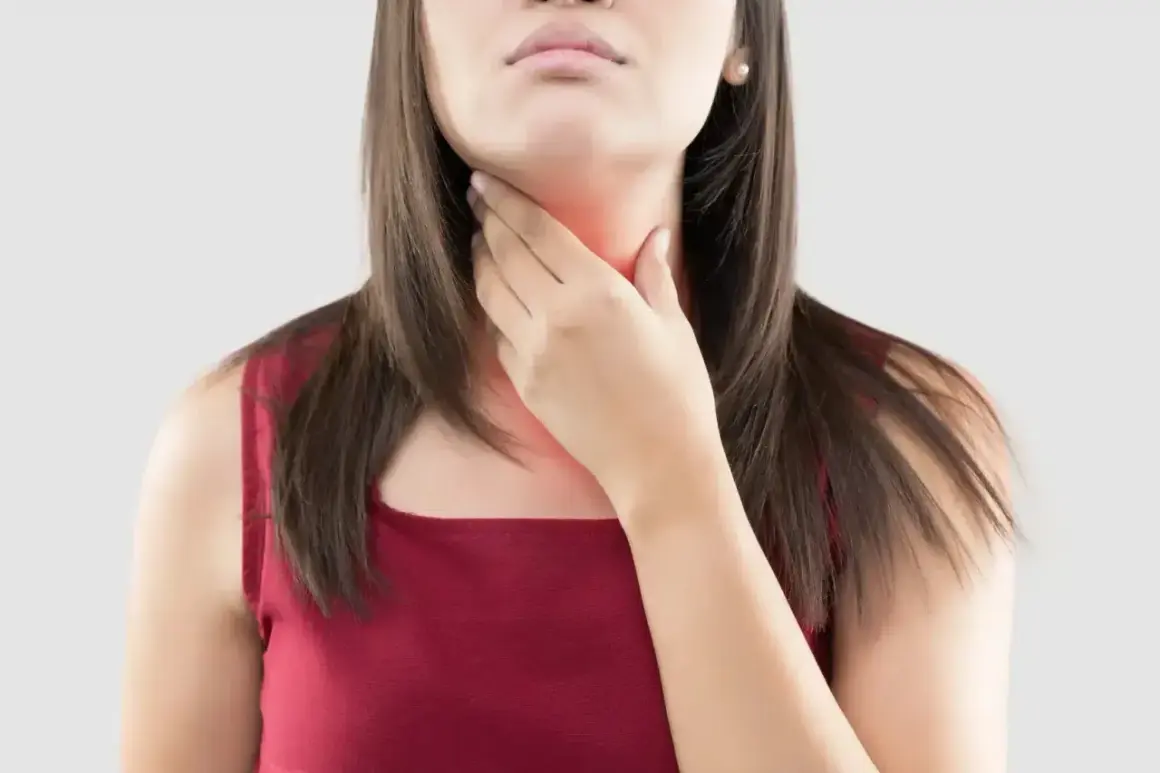 Une femme se tient la gorge, rouge et douloureuse, peut-être à cause d'une cigarette électronique.