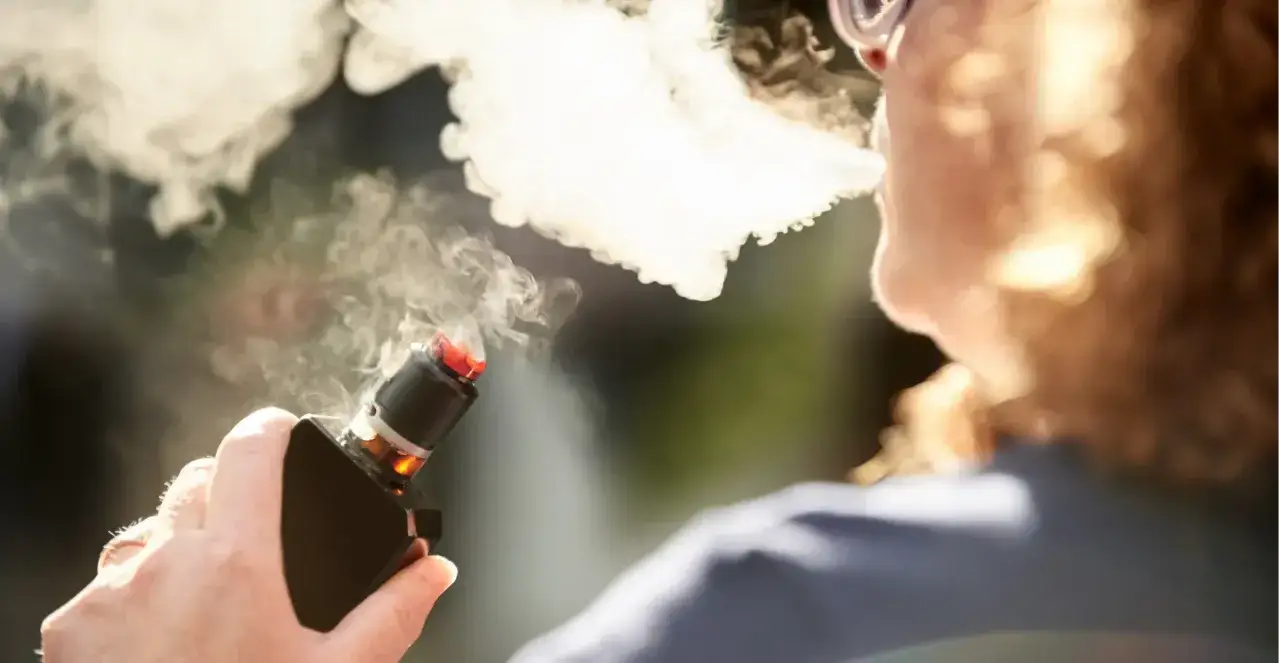Personne vapotant, la vapeur envahit le visage. Une toux sèche se fait sentir, signe d'une possible douleur thoracique liée au vapotage.