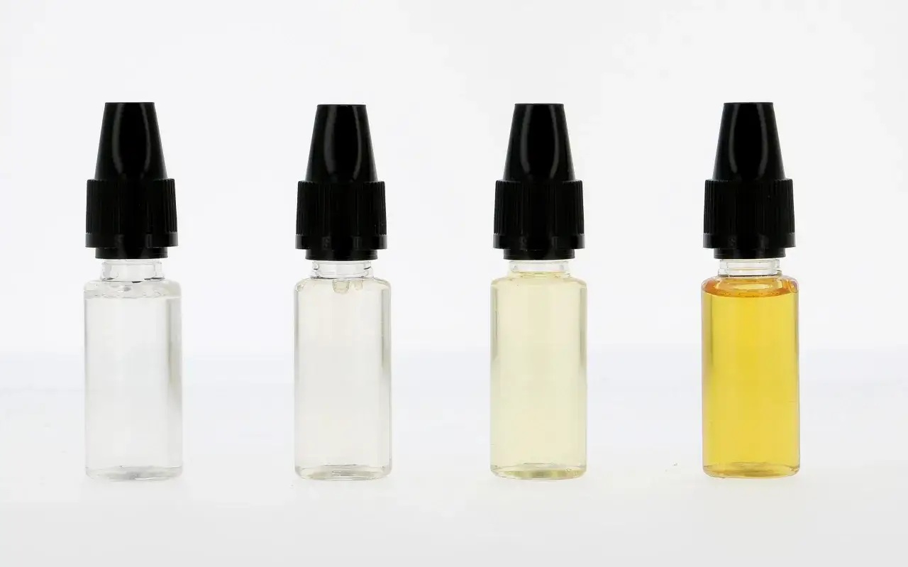 Quatre flacons de e liquide, du transparent au jaune doré, illustrant comment le e liquide change de couleur.