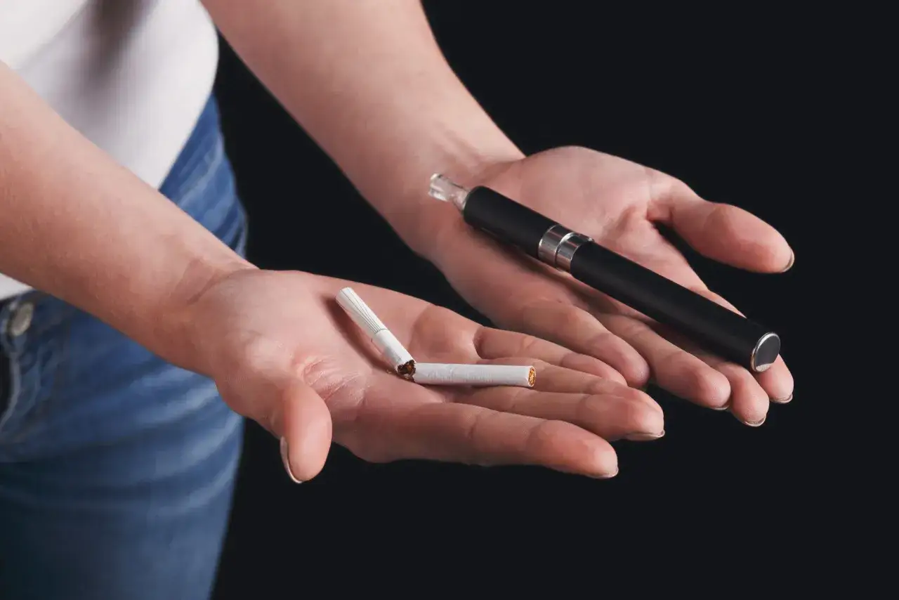 Mains tenant une cigarette cass&eacute;e et une cigarette &eacute;lectronique, symbolisant le sevrage nicotine vapotage.