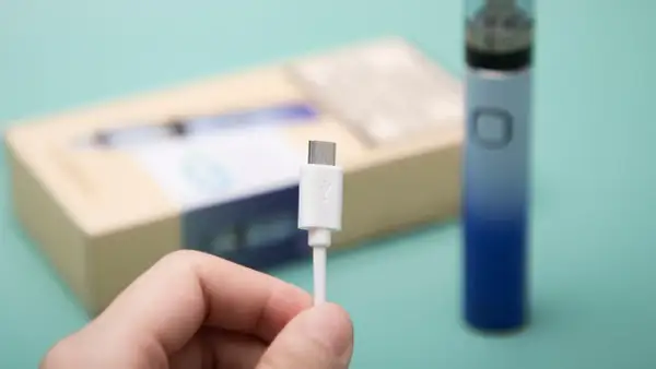 Main tenue, câble USB blanc pour recharger un appareil Innokin low volt.