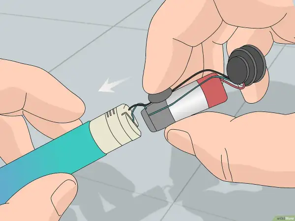 Mains pour recharger les accus d'un appareil électronique. Les fils sont connectés à une batterie et à un composant circulaire.