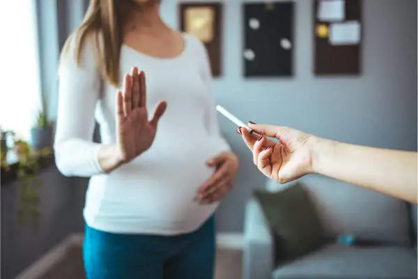 Femme enceinte refuse une cigarette électronique. Elle dit "non" à la tentation, car elle n'arrive pas à arrêter de vapoter.
